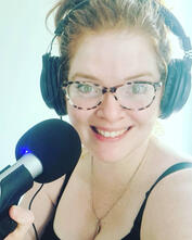Photo of Chole Gage wearing headphones, in front of a mic, looking at camera